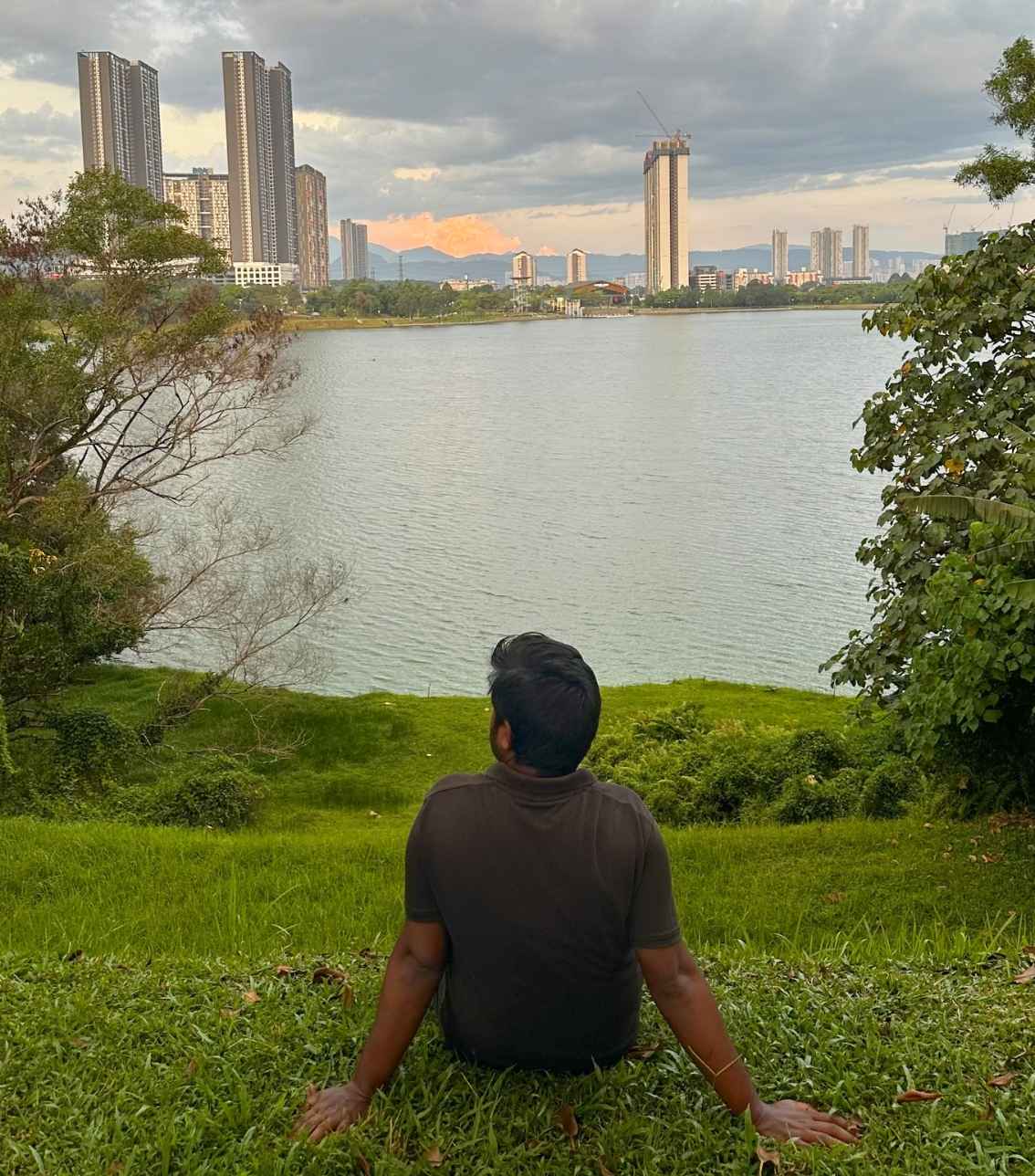 Mo sitting on green grass by a lake in Kuala Lumpur, Malaysia
